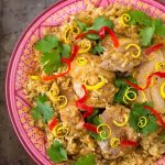 jerk thighs and rice in a colorful patterned bowl on metal background with fork