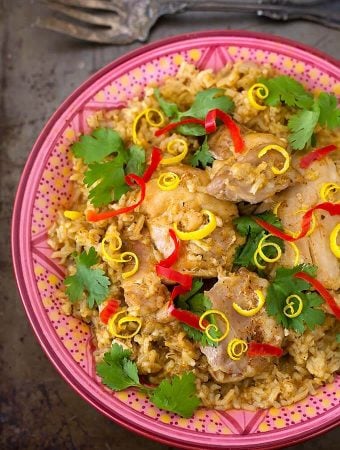 jerk thighs and rice in a colorful patterned bowl on metal background with fork