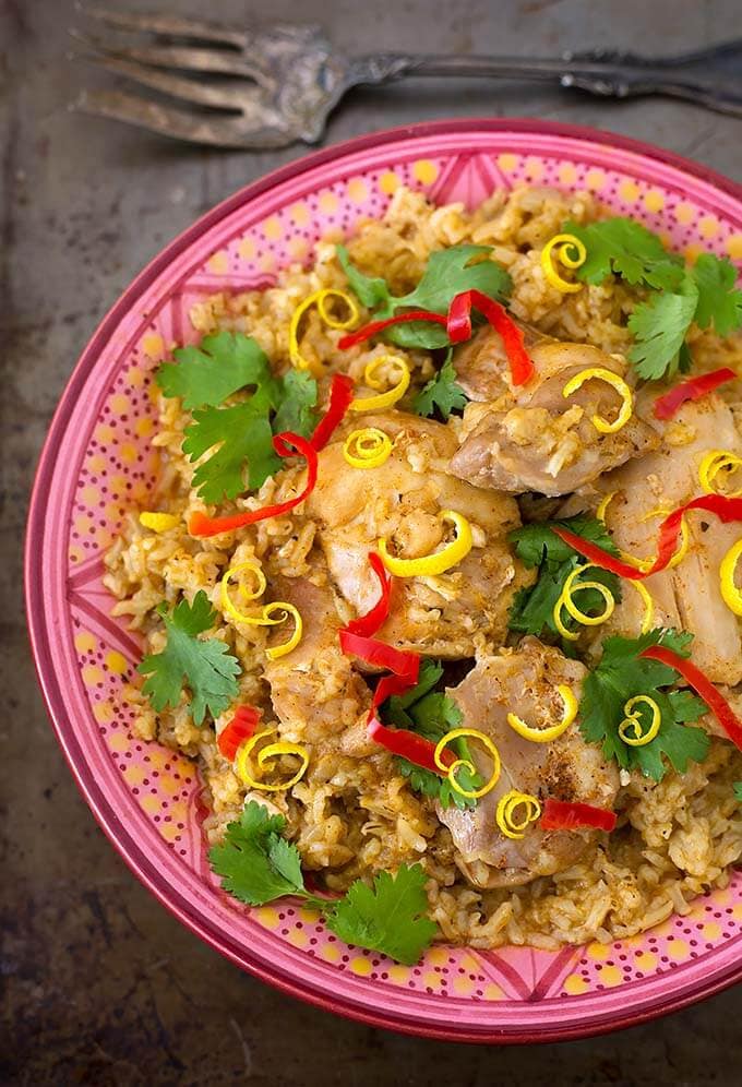 jerk thighs and rice in a colorful patterned bowl on metal background with fork