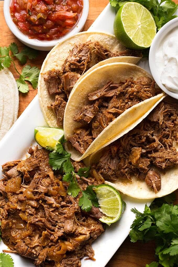 Pork Carnitas in flour tortillas on a white platter with meat