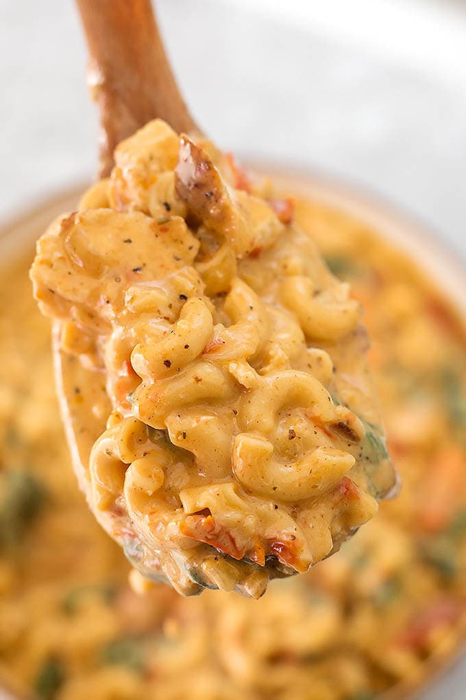 Close up of Creamy Garlic Tuscan Chicken Pasta on a wooden serving spoon