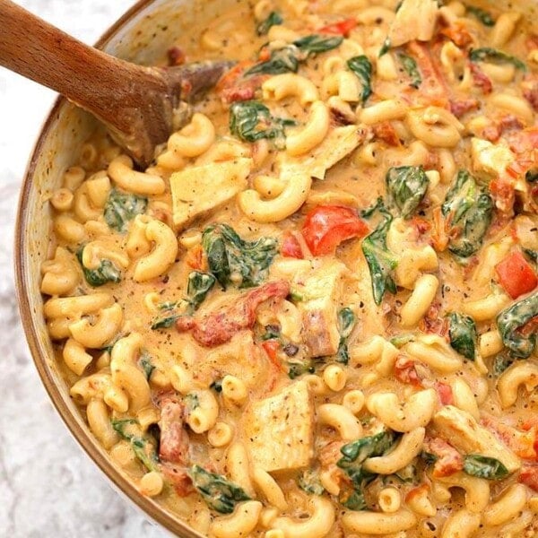 Creamy Garlic Tuscan Chicken Pasta in beige bowl with wooden spoon