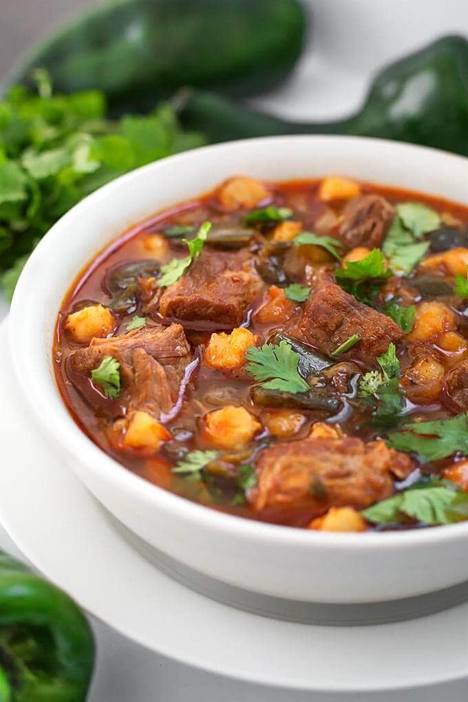 Instant Pot Pork Stew in white bowl next to Poblano chili peppers 