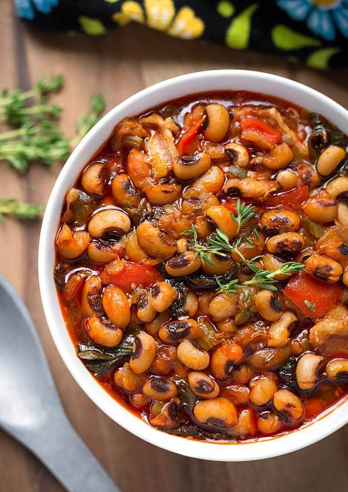 Black-Eyed Peas in a white bowl next to spoon on wooden board