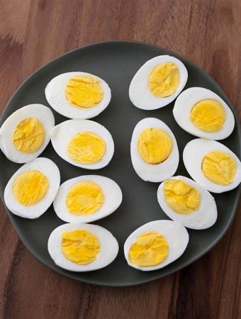Boiled Eggs cut in half on black plate on wood board