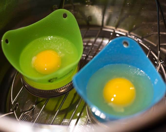 Two molds with egg without shell on trivet in pressure cooker pot