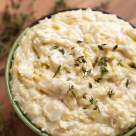 Cheesy Garlic Orzo pasta in a green bowl on a wooden board