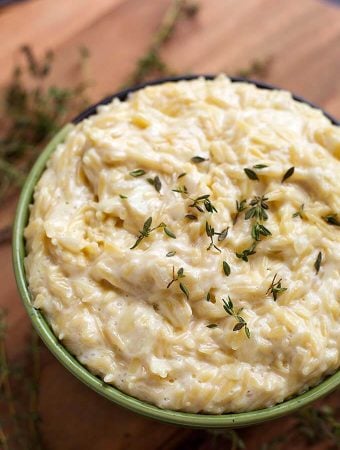 Cheesy Garlic Orzo pasta in a green bowl on a wooden board