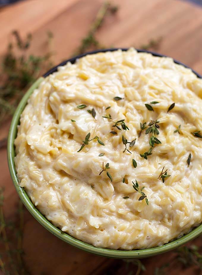 Cheesy Garlic Orzo pasta in a green bowl on a wooden board