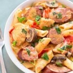 Creamy Cajun Pasta with sausage in a white bowl next to silver fork