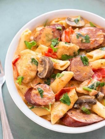 Creamy Cajun Pasta with sausage in a white bowl next to silver fork