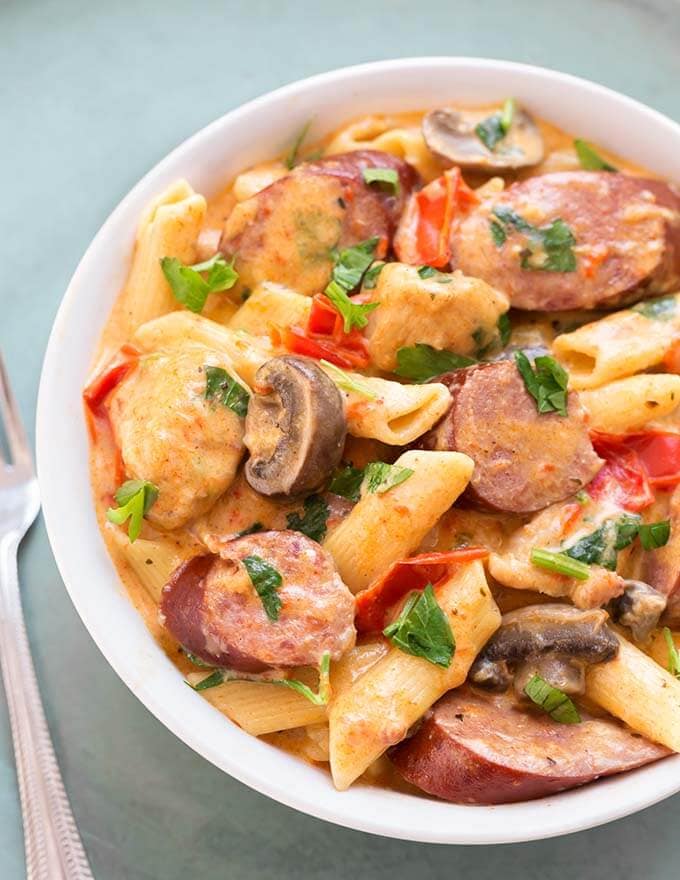 Creamy Cajun Pasta with sausage in a white bowl next to silver fork