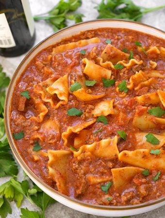 Easy Lasagna Soup in a white bowl with brown rim surrounded by parsley