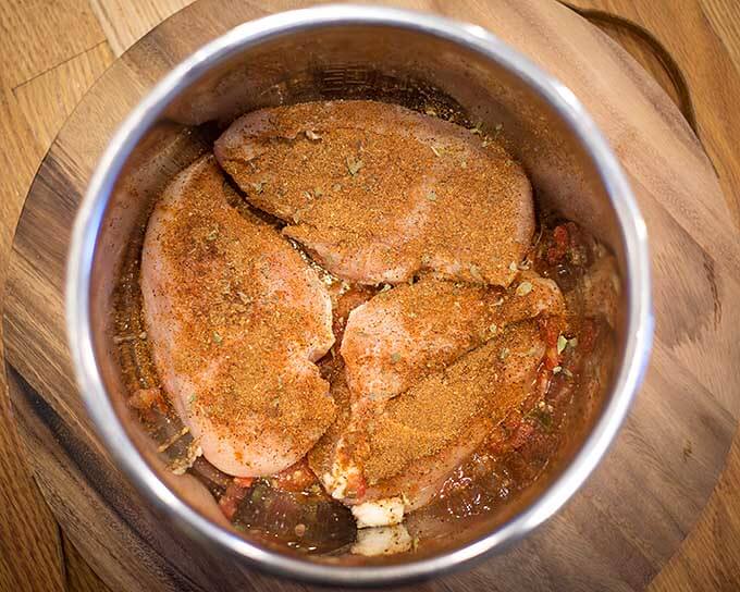 Three seasoned chicken breasts in pressure cooker pot
