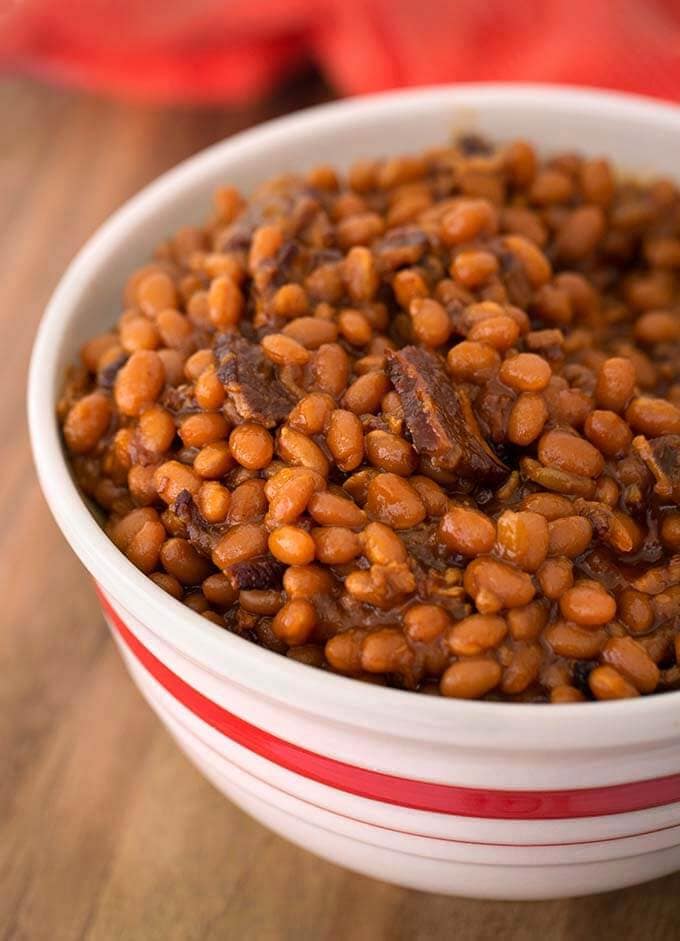 Smoky Sweet Baked Beans in a white bowl with red stripe on wooden board