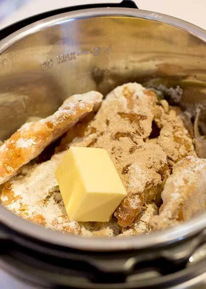 seasoned chicken and cube of butter in pressure cooker pot