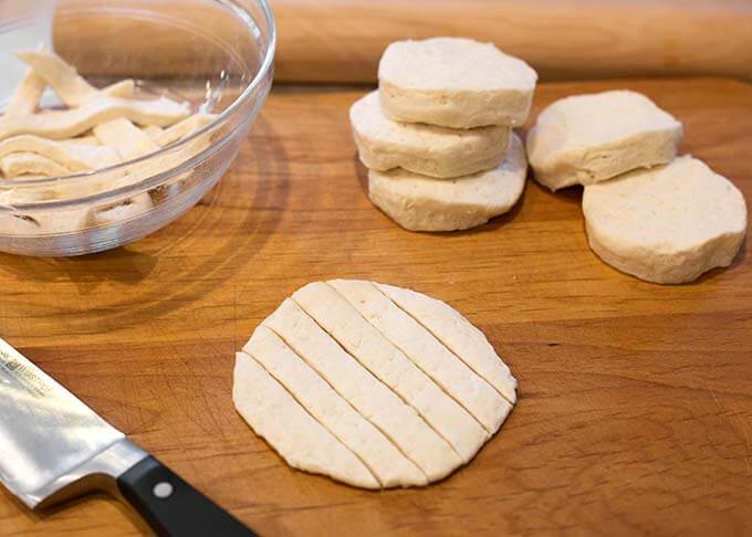 Canned biscuit dough cut into strips on wooden board