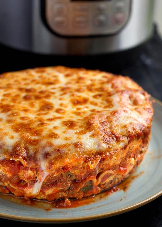 Round Lasagna on a light blue plate in front of pressure cooker