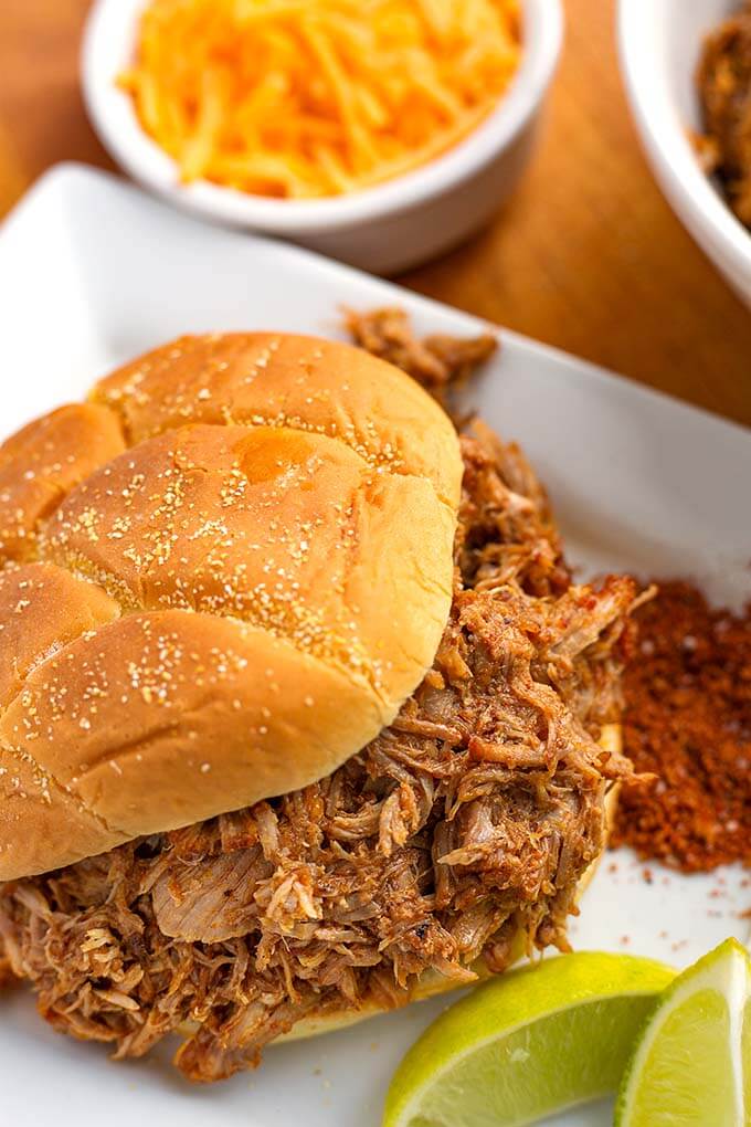 Close up of Instant Pot Pulled Pork on a hamburger bun on a white serving platter