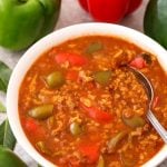 Stuffed Pepper Soup in white bowl with spoon with green and red bell peppers in background