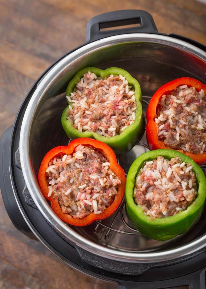 Four Instant Pot Stuffed Peppers two green and two red on a trivet in a pressure cooker