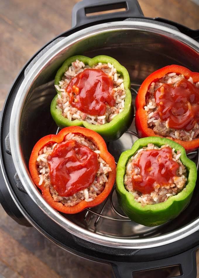 Four Instant Pot Stuffed Peppers topped with a dollop of ketchup on trivet in a pressure cooker