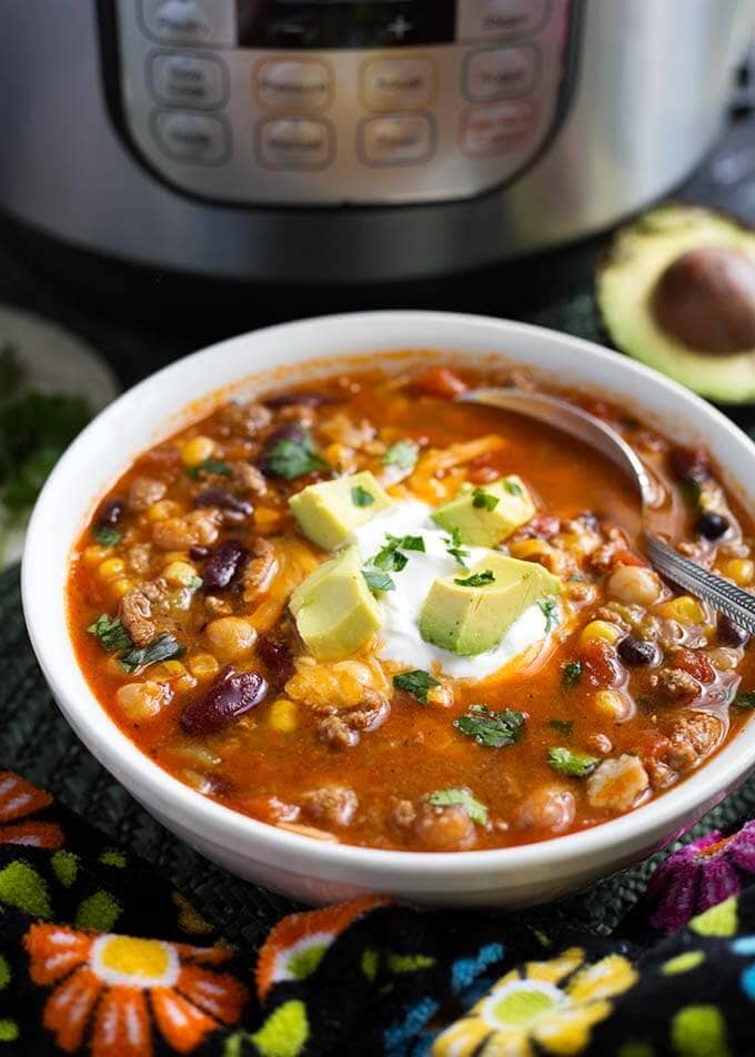 Taco Soup in a white bowl topped with sour cream and diced avocado