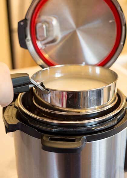 pan gripper holding small pot of rice and water above pressure cooker