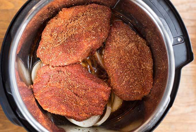 three seasoned pork shoulder sections in pressure cooker pot