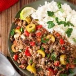 Picadillo with white rice on dark green plate next to silver spoon