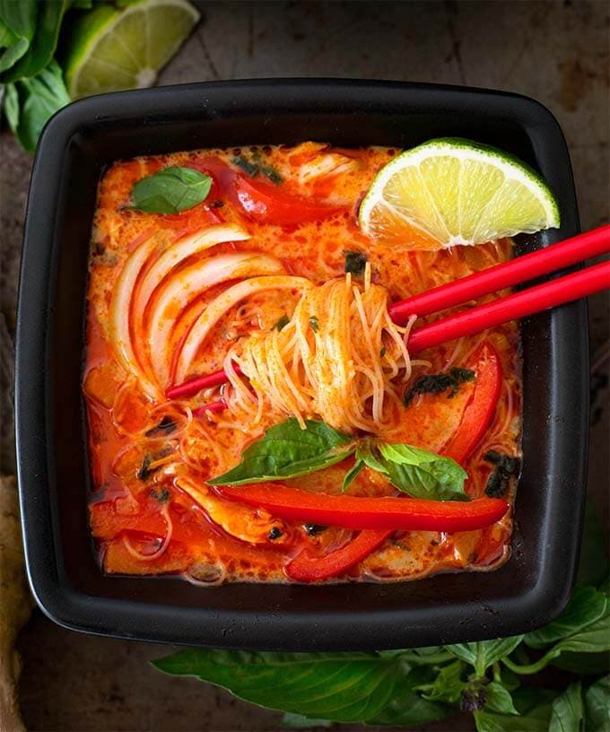 Red Curry Coconut Noodle Soup in black square bowl with red chopsticks