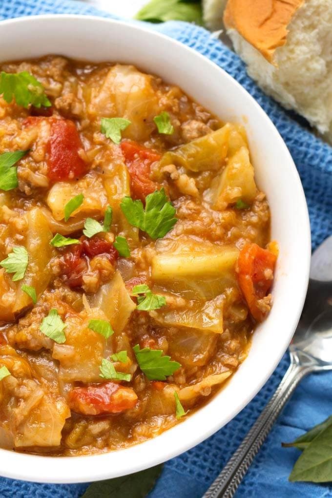 Close up of Unstuffed Cabbage Rolls in white bowl and spoon on blue kitchen towel