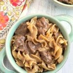 Beef and Noodles in turquoise bowl with handles on light wood background