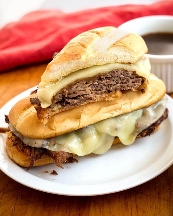 Half of a French Dip Sandwich on a whole sandwich on a white plate