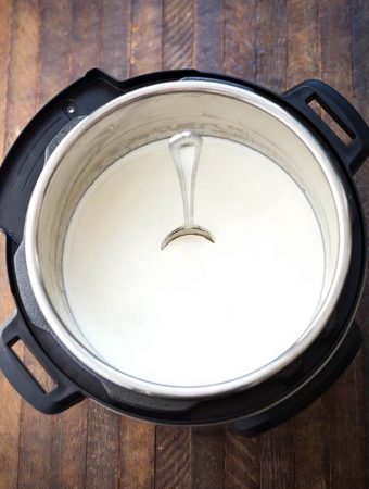 Yogurt in pressure cooker with spoon standing straight in yogurt