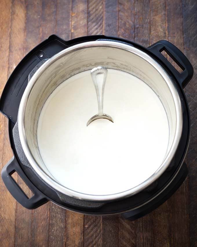 Yogurt in pressure cooker with spoon standing straight in yogurt