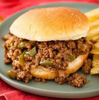 Sloppy Joes on hamburger bun next to chips all on blue plate