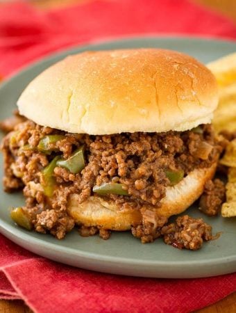 Sloppy Joes on hamburger bun next to chips all on blue plate