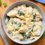 pressure cooker Tortellini Alfredo in grey bowl on wooden board