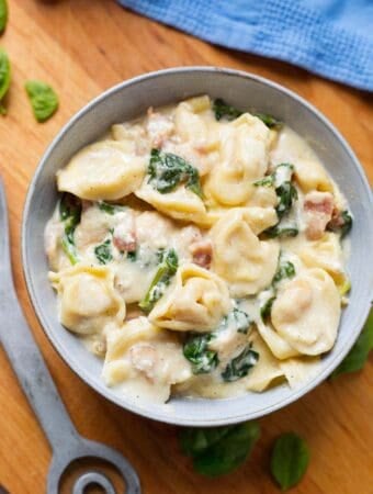 pressure cooker Tortellini Alfredo in grey bowl on wooden board