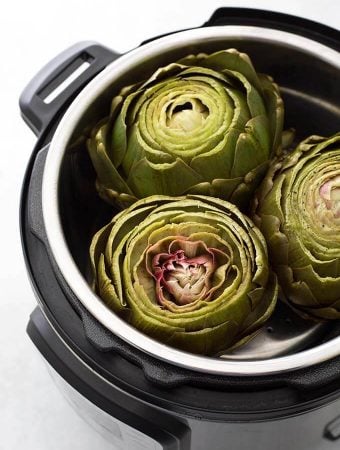 three Whole Steamed Artichokes in a pressure cooker