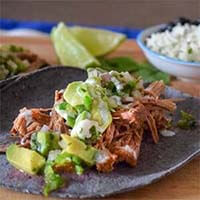 Instant Pot Beef Tacos with Avocado Salsa on blue corn tortillas on a wooden board