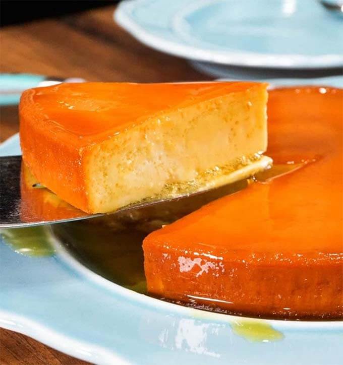 Slice of flan being served from a white plate