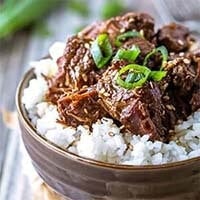 Instant Pot Korean Beef over rice in a brown bowl