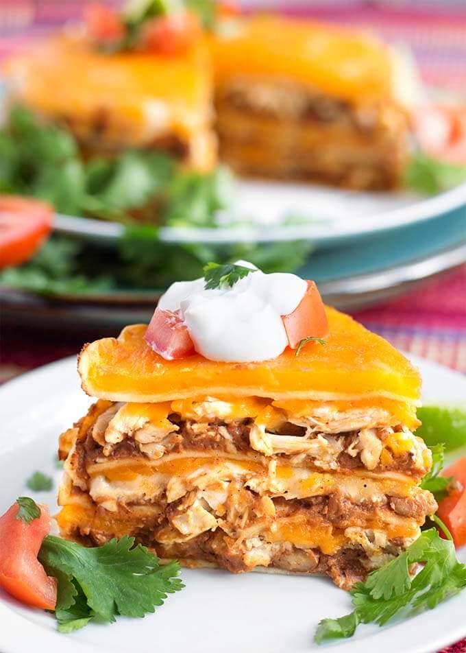 Closeup of a slice of Chicken Taco Pie on a white plate topped with sour cream