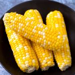 Four Corn on the Cobs on a black plate