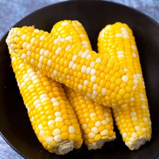 Four Corn on the Cobs on a black plate