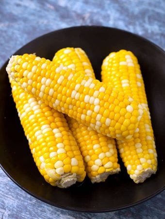 Four Corn on the Cobs on a black plate