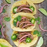 Top view of three Beef Barbacoa Tacos on a baking sheet