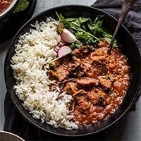 Persian Beef Stew with rice and vegetable in a black bowl with a spoon